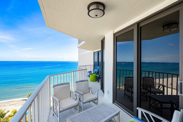 balcony featuring a water view and a beach view