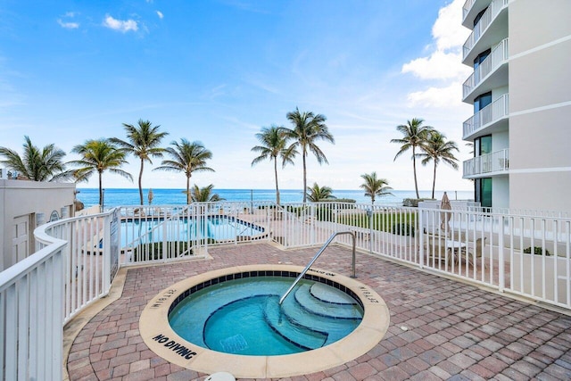 view of pool with a water view and a hot tub