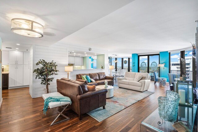 living room featuring hardwood / wood-style floors, wood walls, and a wall of windows