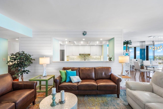 living room with hardwood / wood-style floors, wooden walls, and an inviting chandelier