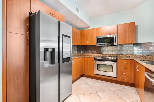 kitchen featuring light stone countertops, appliances with stainless steel finishes, tasteful backsplash, and light tile patterned floors