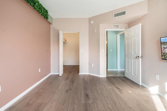 unfurnished bedroom featuring a closet, a spacious closet, and light hardwood / wood-style flooring