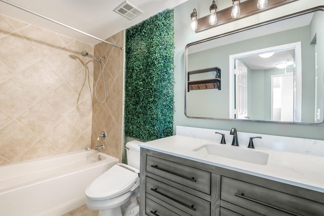 full bathroom featuring tiled shower / bath combo, toilet, and vanity