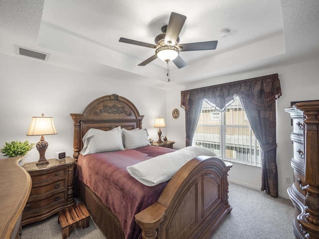 carpeted bedroom with a raised ceiling, ceiling fan, and a textured ceiling