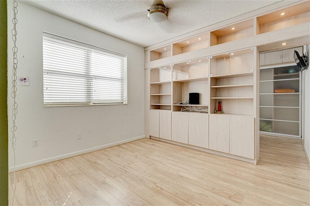 unfurnished living room featuring ceiling fan, light hardwood / wood-style floors, and a textured ceiling