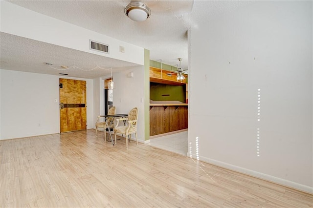 living room featuring ceiling fan, hardwood / wood-style flooring, and a textured ceiling