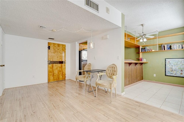 unfurnished room with ceiling fan, a textured ceiling, and light hardwood / wood-style flooring