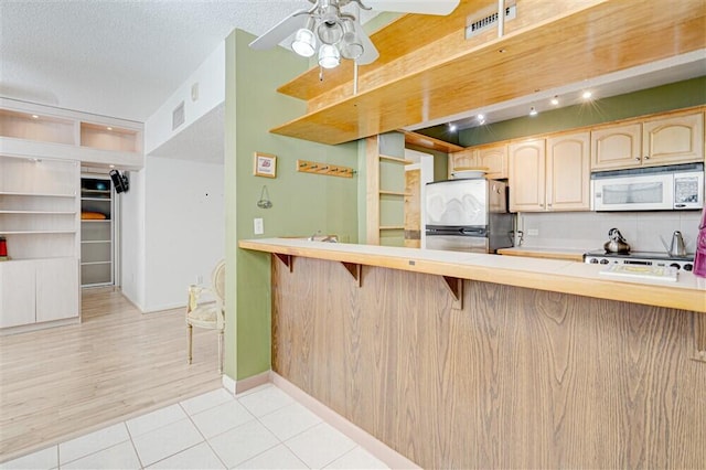 kitchen with stainless steel refrigerator, a kitchen breakfast bar, range, kitchen peninsula, and a textured ceiling