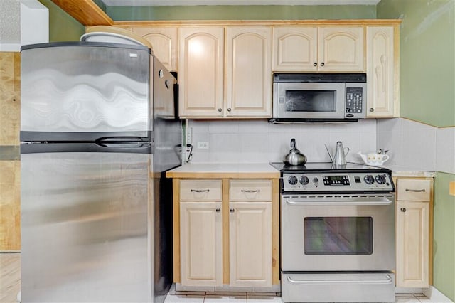 kitchen with appliances with stainless steel finishes, light brown cabinets, and backsplash