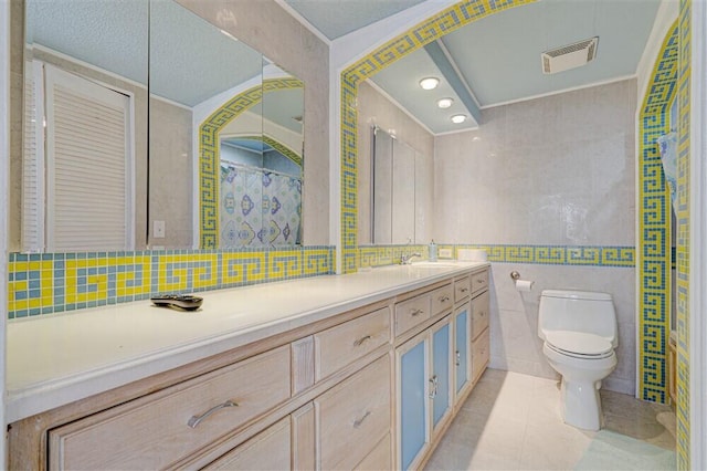 bathroom with tile walls, vanity, tile patterned floors, toilet, and walk in shower