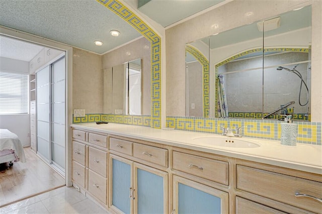 bathroom featuring walk in shower, tile patterned floors, a textured ceiling, vanity, and decorative backsplash