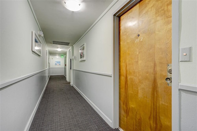 hallway with crown molding and dark carpet