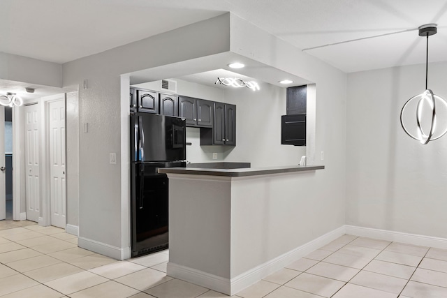 kitchen with black refrigerator, light tile patterned floors, and kitchen peninsula