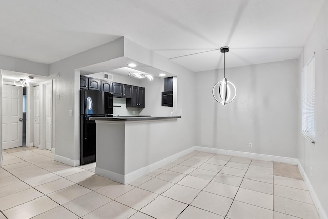 kitchen featuring plenty of natural light, black refrigerator, light tile patterned floors, and kitchen peninsula