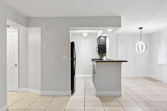 kitchen with black fridge, decorative light fixtures, kitchen peninsula, and light tile patterned floors