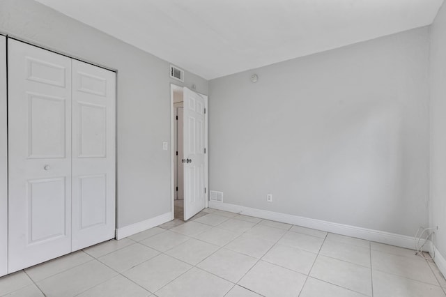 unfurnished bedroom with light tile patterned flooring and a closet