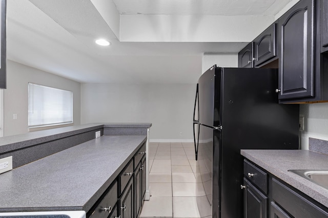 kitchen with black refrigerator, light tile patterned flooring, and sink