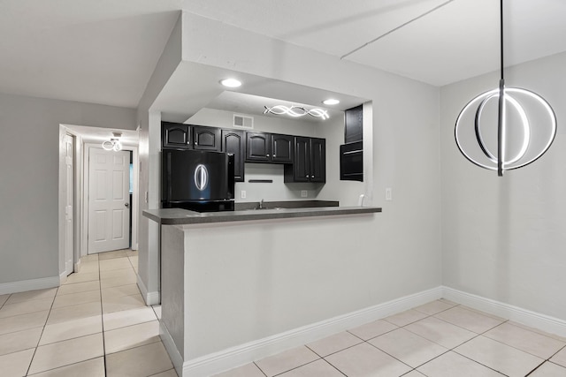 kitchen with fridge, sink, light tile patterned floors, and kitchen peninsula