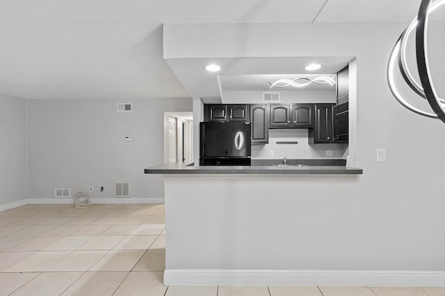 kitchen with sink, light tile patterned floors, fridge, and kitchen peninsula