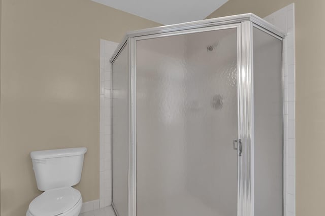 bathroom with tile patterned flooring, toilet, and a shower with shower door