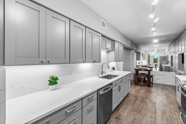 kitchen featuring track lighting, sink, dishwasher, gray cabinets, and dark hardwood / wood-style floors