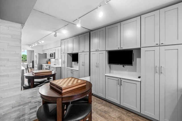 kitchen featuring hardwood / wood-style flooring, gray cabinets, appliances with stainless steel finishes, and track lighting