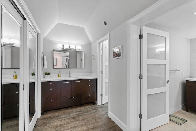 bathroom with hardwood / wood-style flooring, vanity, and vaulted ceiling