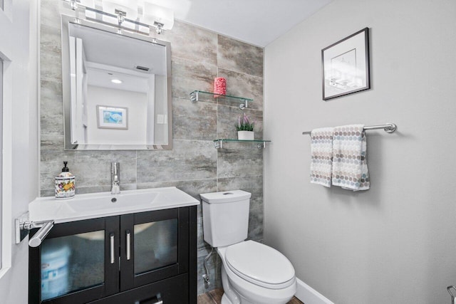 bathroom featuring vanity, tile walls, and toilet