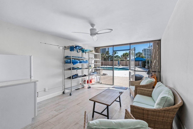 living room featuring ceiling fan, light hardwood / wood-style floors, and a wall of windows