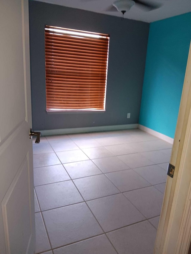 tiled empty room featuring ceiling fan