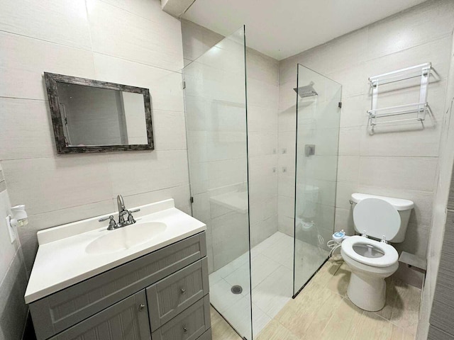 bathroom featuring vanity, toilet, tile walls, and a tile shower