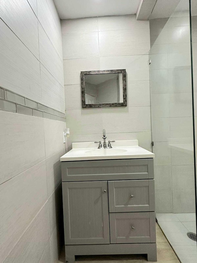 bathroom with vanity, a shower, and tile walls