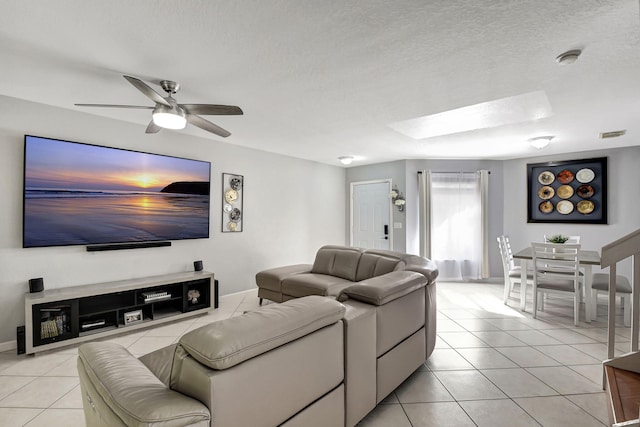 living room with light tile patterned floors, a textured ceiling, a skylight, and ceiling fan