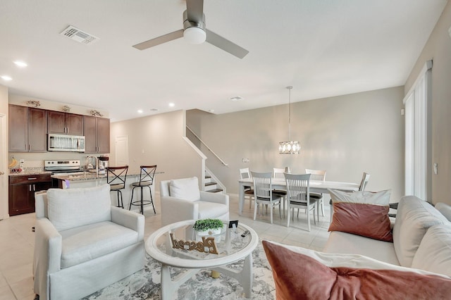 tiled living room with ceiling fan with notable chandelier and sink