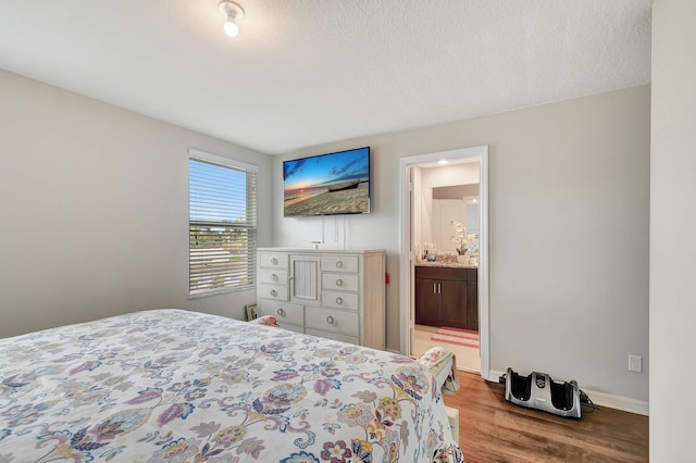 bedroom featuring a textured ceiling, connected bathroom, and light hardwood / wood-style flooring