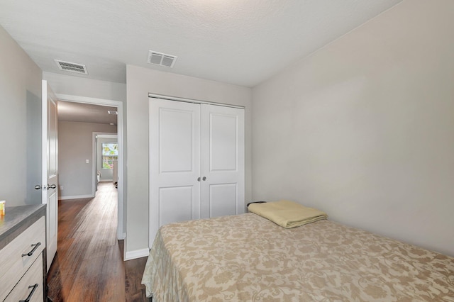 bedroom with dark hardwood / wood-style flooring, a textured ceiling, and a closet