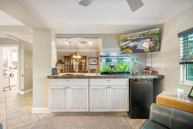 kitchen featuring white cabinets, ceiling fan with notable chandelier, black fridge, decorative light fixtures, and light tile patterned flooring