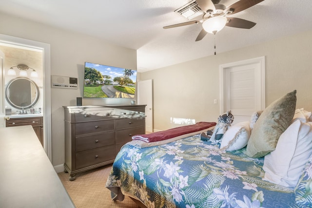 bedroom featuring ceiling fan, light colored carpet, sink, and ensuite bath