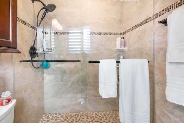 bathroom with toilet, tile walls, and tiled shower