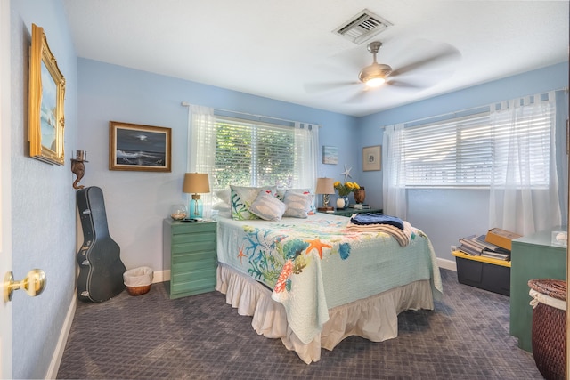 bedroom with multiple windows, ceiling fan, and dark colored carpet