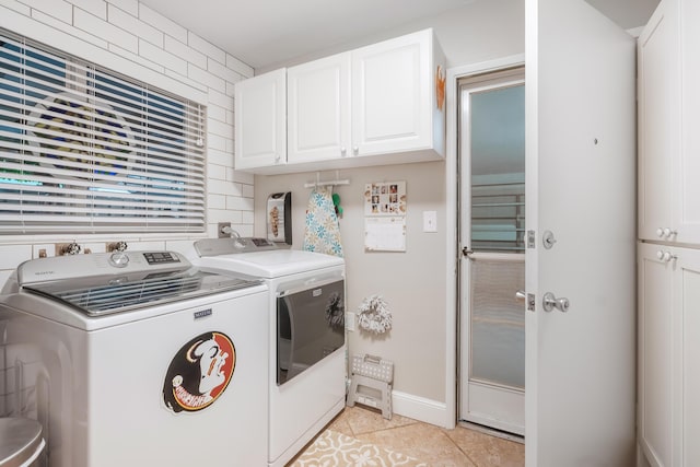 clothes washing area featuring cabinets, light tile patterned floors, and washer and clothes dryer