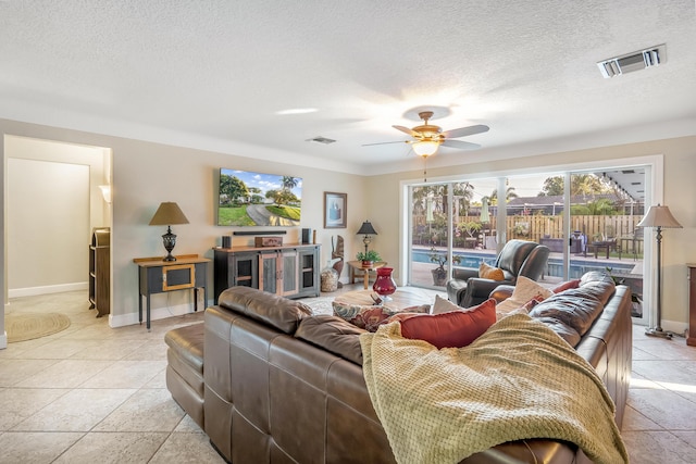 living room with ceiling fan, light tile patterned floors, and a textured ceiling