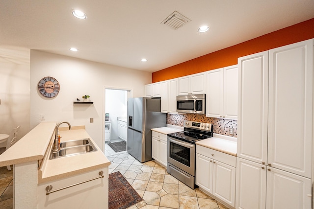 kitchen with light tile patterned flooring, sink, white cabinetry, stainless steel appliances, and backsplash