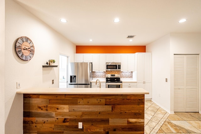 kitchen featuring tasteful backsplash, white cabinetry, sink, kitchen peninsula, and stainless steel appliances