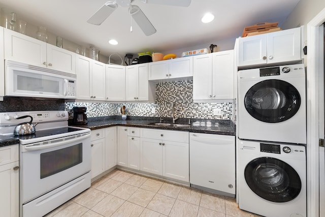 kitchen featuring white appliances, white cabinetry, stacked washer / drying machine, and sink