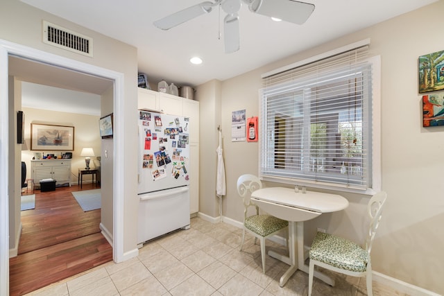 kitchen with white cabinets, light wood-type flooring, white fridge, and ceiling fan