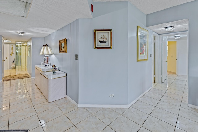 hallway featuring a textured ceiling and light tile patterned flooring