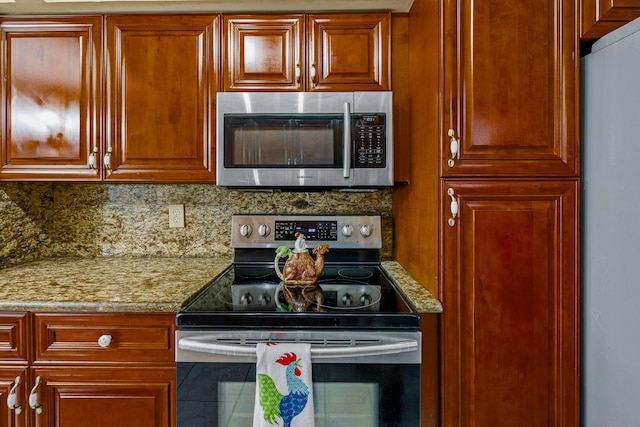 kitchen featuring light stone counters, stainless steel appliances, and tasteful backsplash