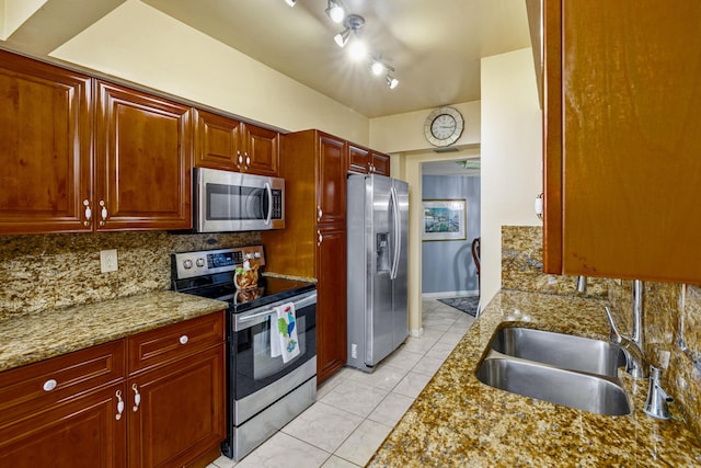 kitchen featuring rail lighting, decorative backsplash, light tile patterned floors, light stone counters, and stainless steel appliances