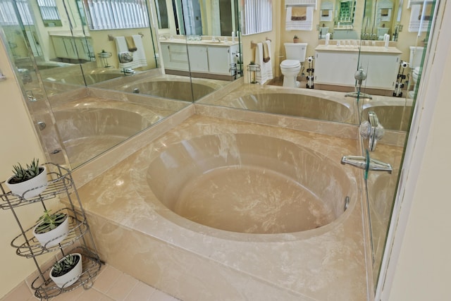 bathroom featuring tile patterned floors, vanity, toilet, and tiled bath